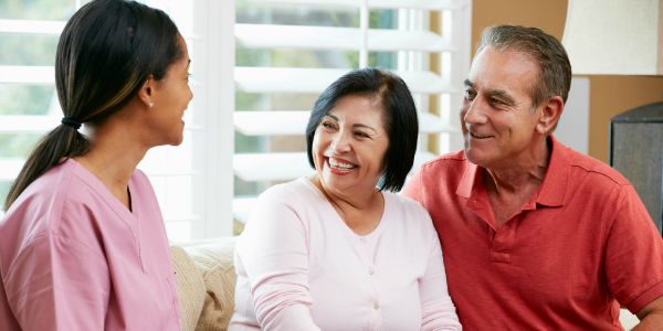 Nurse Making Notes During Home Visit With Senior Couple Nurse Making Notes During Home Visit With Senior Couple